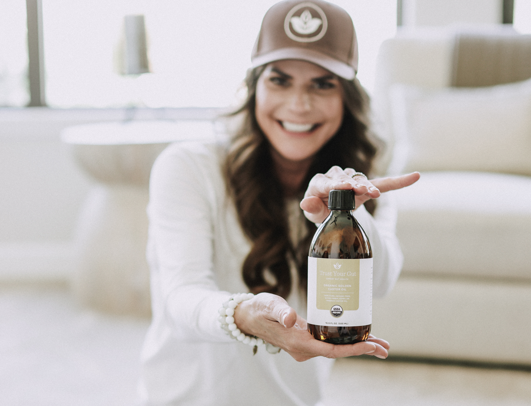 Woman holding a bottle of Trust Your Gut  liquid in a home setting